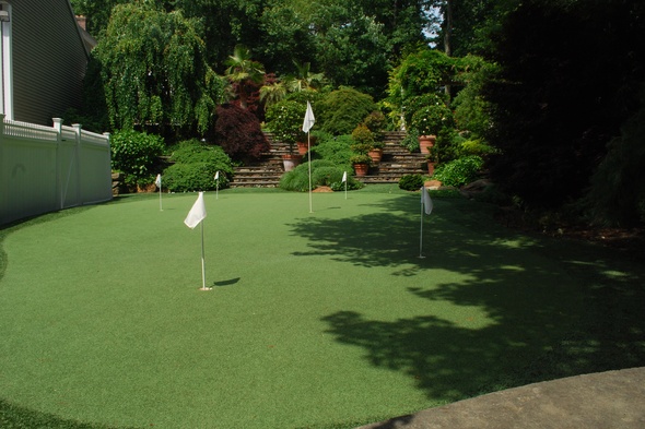 Jacksonville Synthetic grass golf green with flags in a landscaped backyard