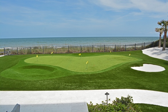 Jacksonville Synthetic grass golf green by the sea with yellow flags and a sand bunker